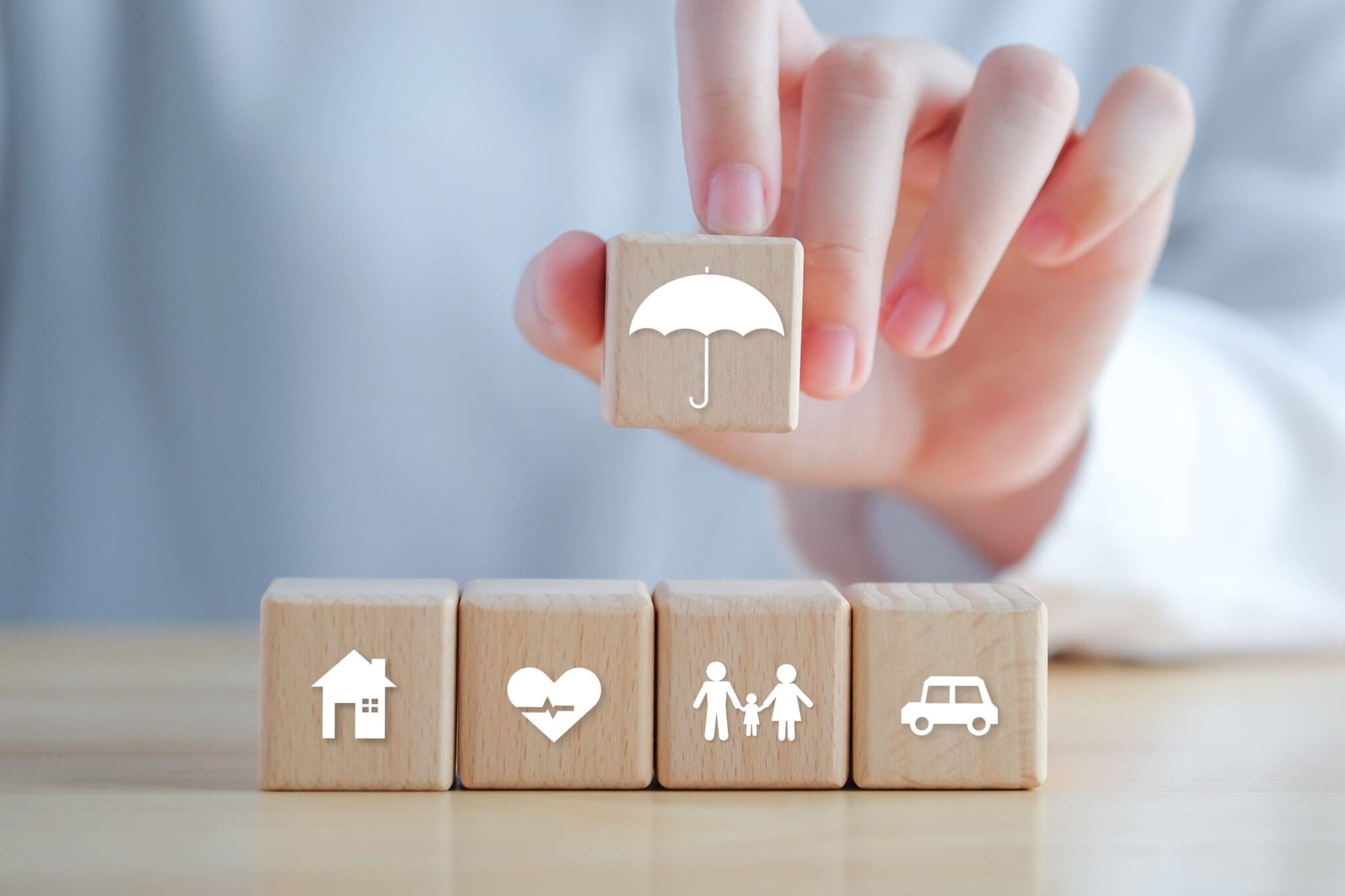 Hand holding umbrella over wooden blocks.