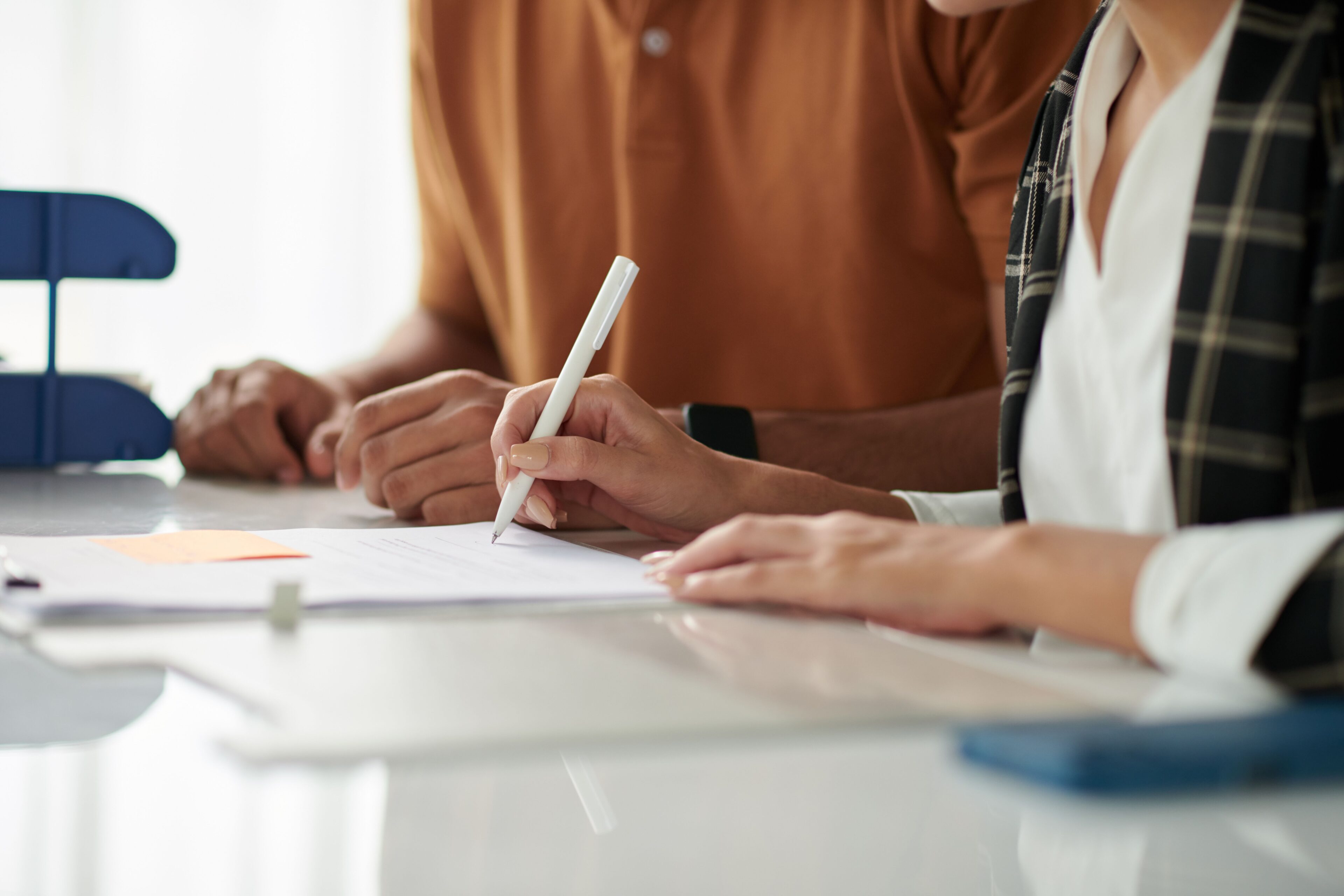 Person reviewing documents with pen and paper.