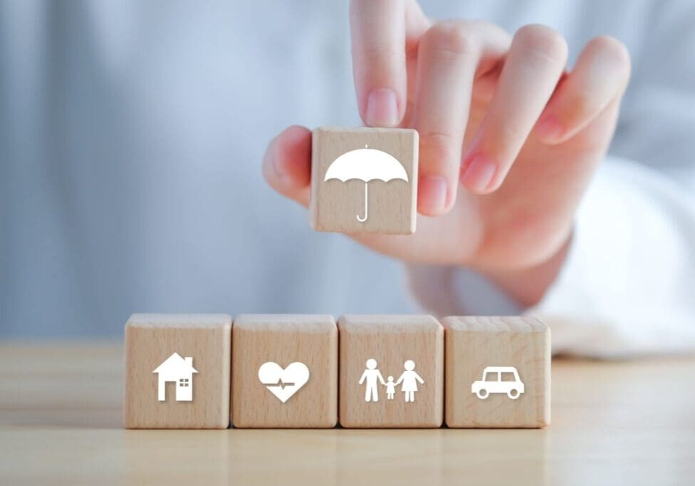 Hand holding umbrella over wooden blocks.